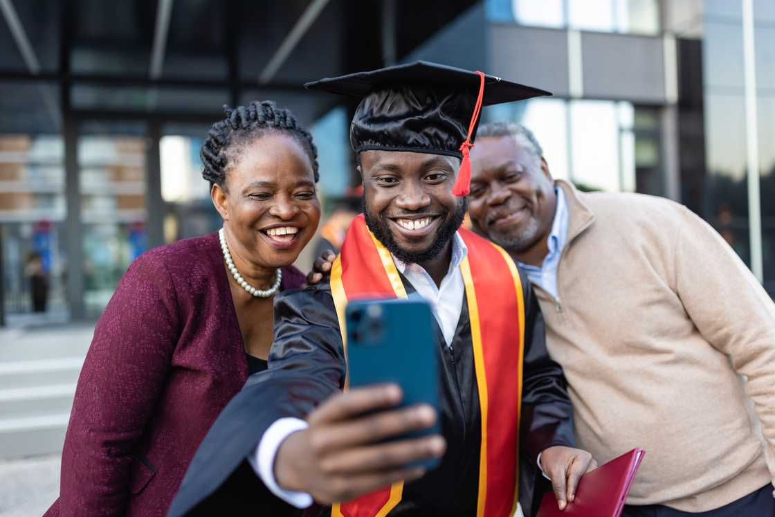 A student celebrates his graduation alongside his parents A student celebrates his graduation alongside his parents