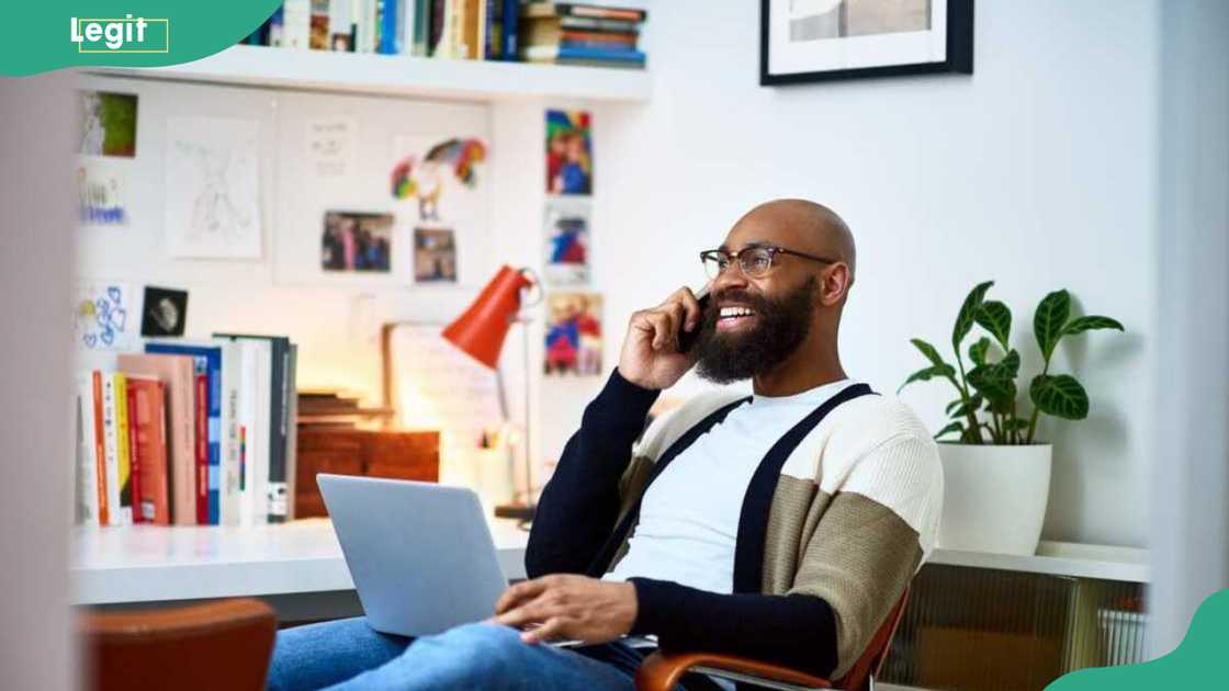 A man sitting on a chair with a laptop on a phone call A man sitting on a chair with a laptop on a phone call