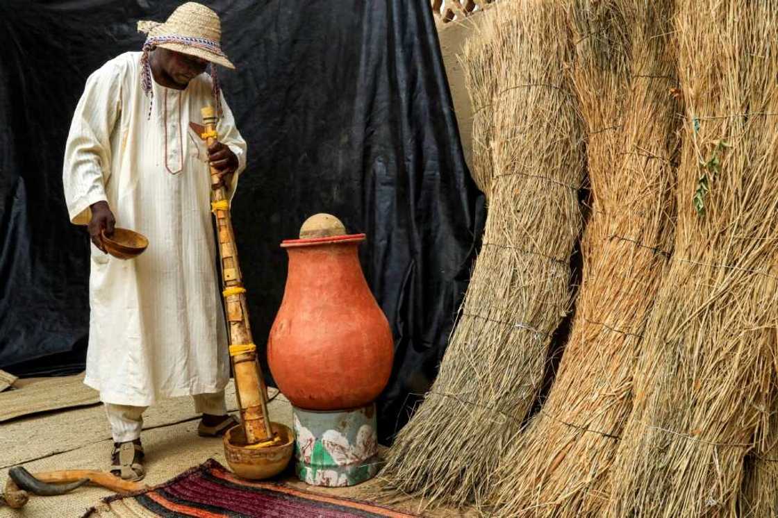 Dafallah al-Haj Ali Mustafa pours water down the pipe of the traditional "wazza" instrument to wet and soften it before playing Dafallah al-Haj Ali Mustafa pours water down the pipe of the traditional "wazza" instrument to wet and soften it before playing