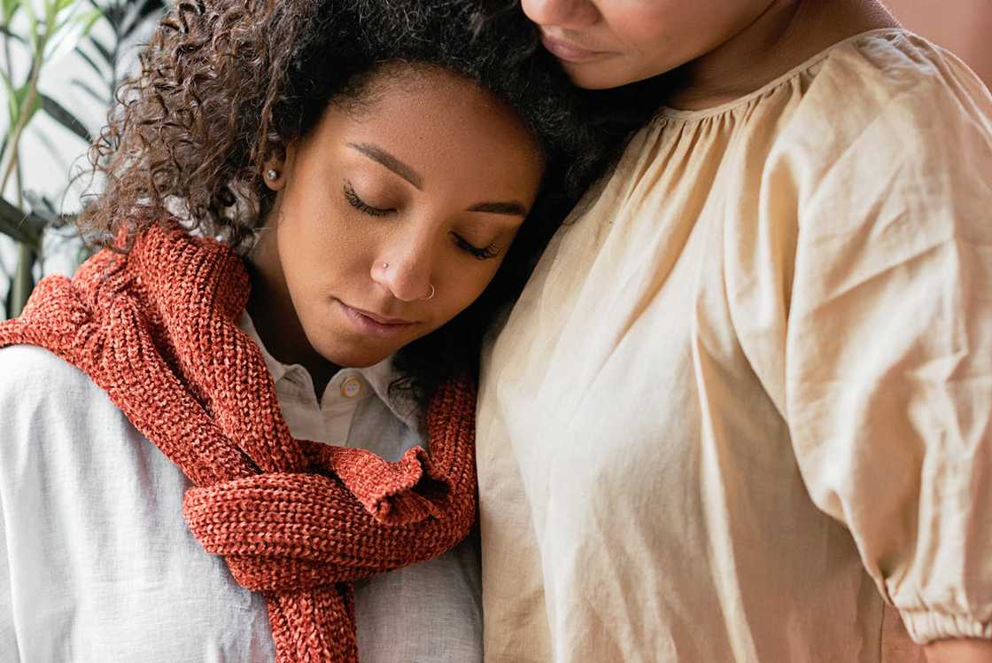 A woman rests her head on another person’s shoulder. A woman rests her head on another person’s shoulder.