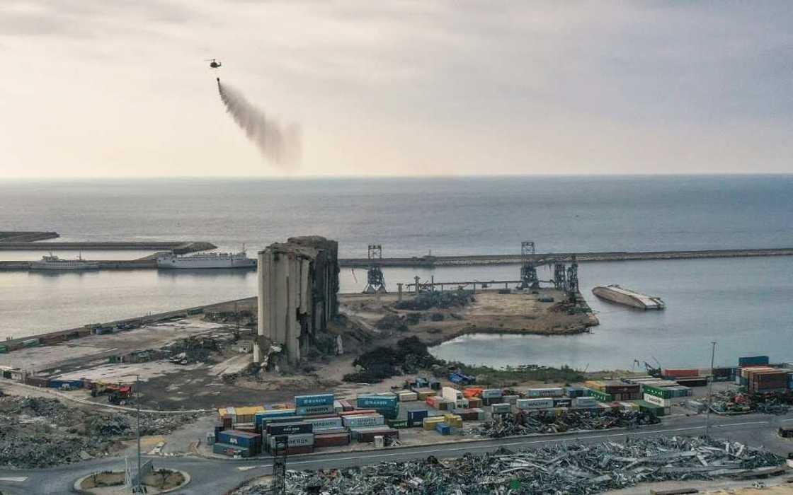 A Lebanese army helicopter releases water over the heavily damaged grain silos at the port of the capital Beirut