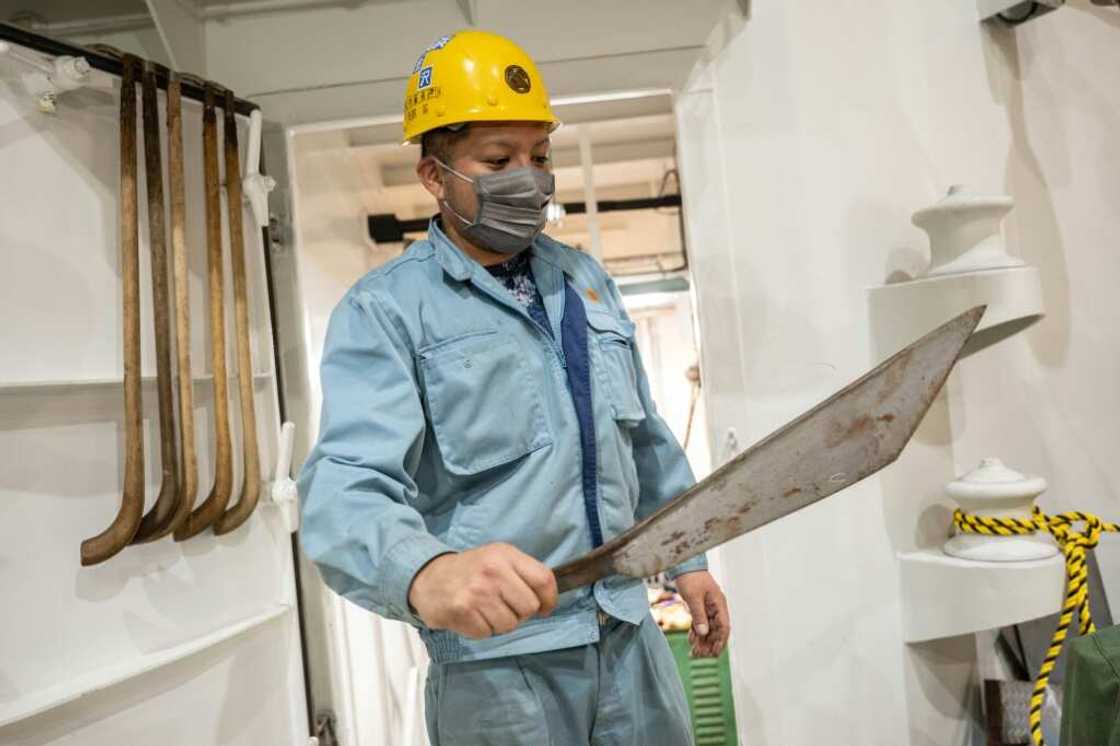 A crew member shows a large knife for cutting up whales on Japan's new whaling mothership, the Kangei Maru