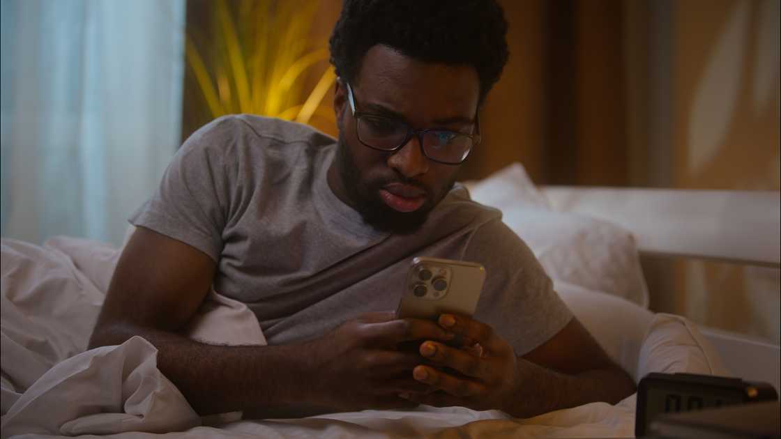 a shocked man looking at his phone at night