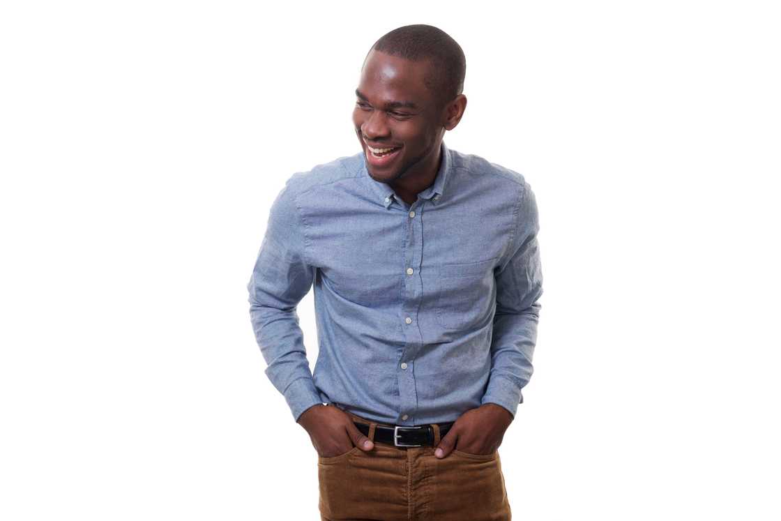 A young man on a lue chambray shirt and brown pants.