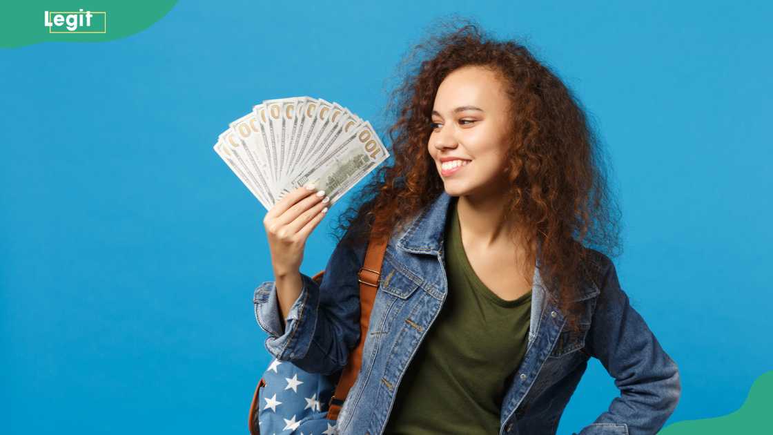 A young girl teen student holding money isolated on a blue background studio portrait A young girl teen student holding money isolated on a blue background studio portrait