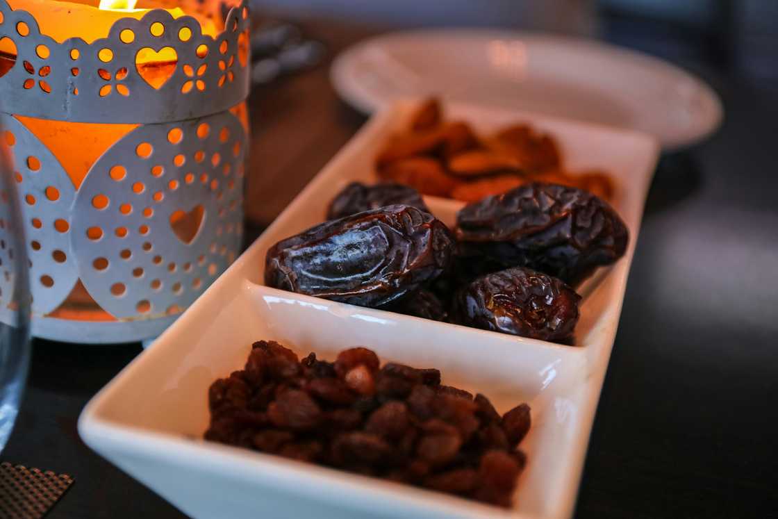 A close-up of raisins and dates on a white rectangular dish with compartments A close-up of raisins and dates on a white rectangular dish with compartments