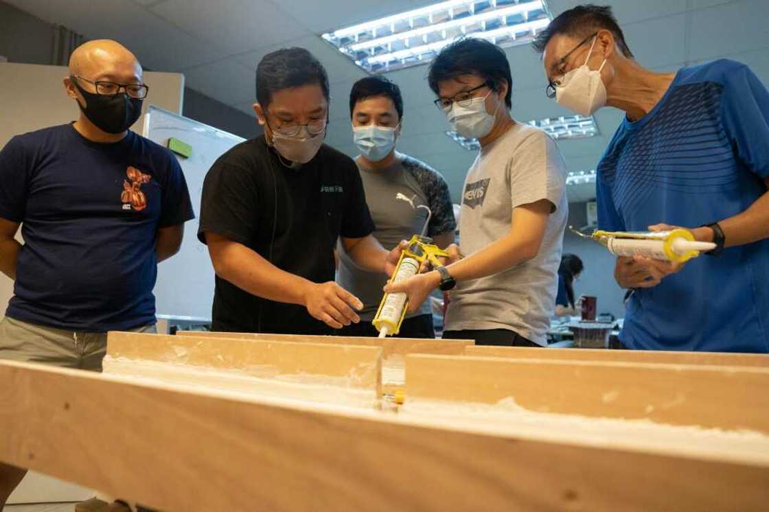 Lau Chun-yu (centre L), co-founder of Renobro, teaches caulking skills to students taking a home-repair class in Hong Kong -- he said he hadn't expected so many people would be emigrating Lau Chun-yu (centre L), co-founder of Renobro, teaches caulking skills to students taking a home-repair class in Hong Kong -- he said he hadn't expected so many people would be emigrating