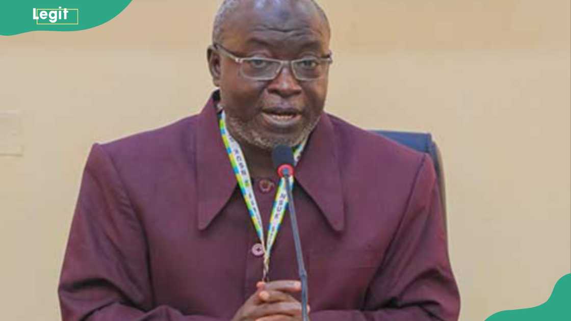 Emmanuel Kucha giving a speech in a brown outfit