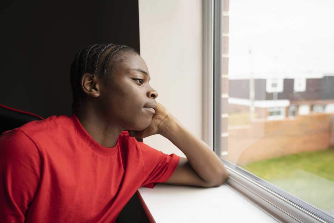 A young boy looking out the window as he ponders A young boy looking out the window as he ponders