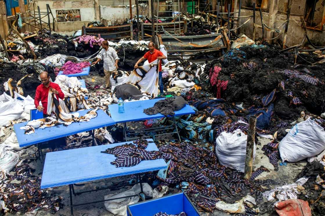 Workers sort through the remains of a garment factory torched during the protests Workers sort through the remains of a garment factory torched during the protests