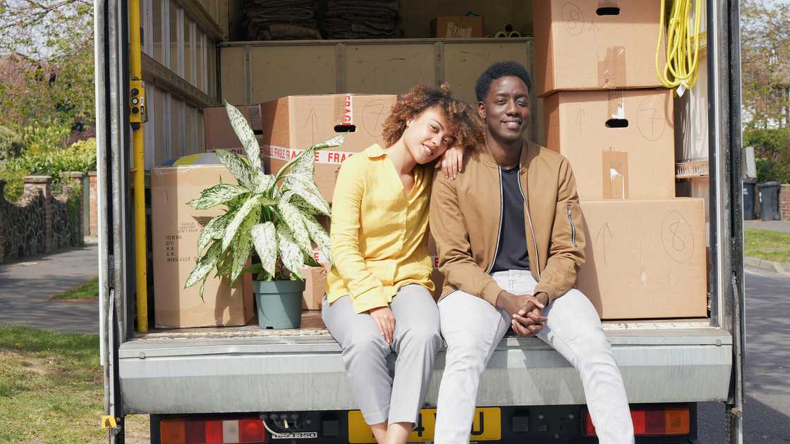 A couple seated at the back of a truck A couple seated at the back of a truck