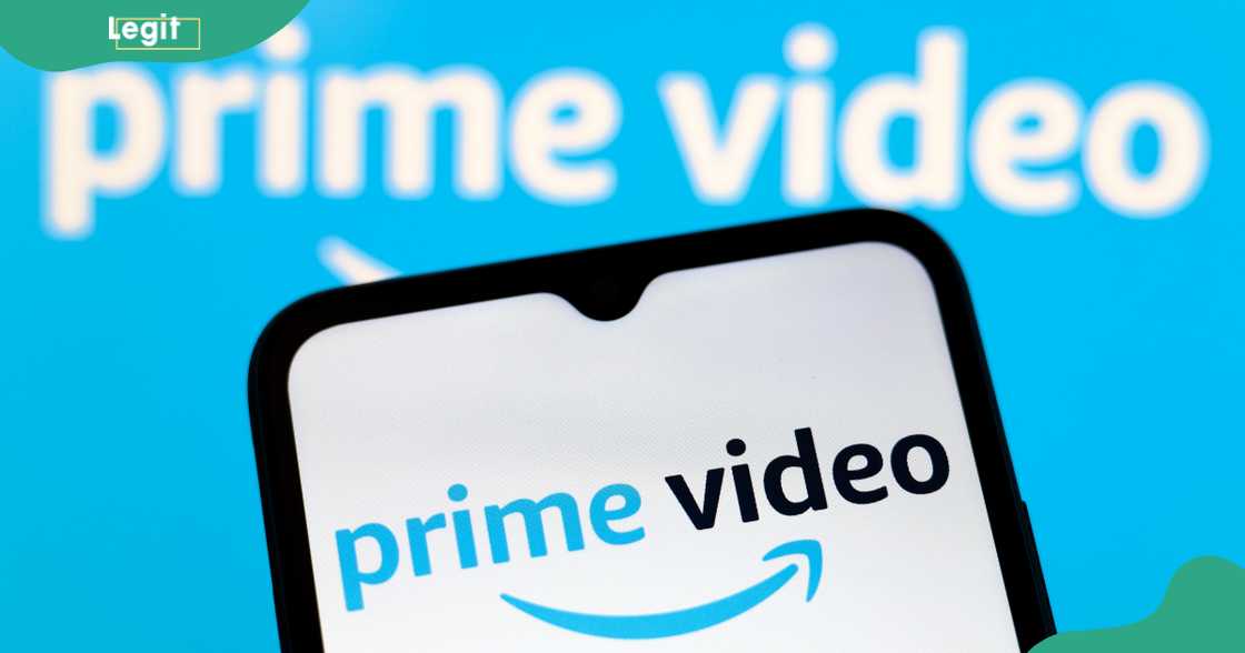 The Amazon Prime Video logo appears on the screen of a smartphone and in the background on the computer screen. The Amazon Prime Video logo appears on the screen of a smartphone and in the background on the computer screen.