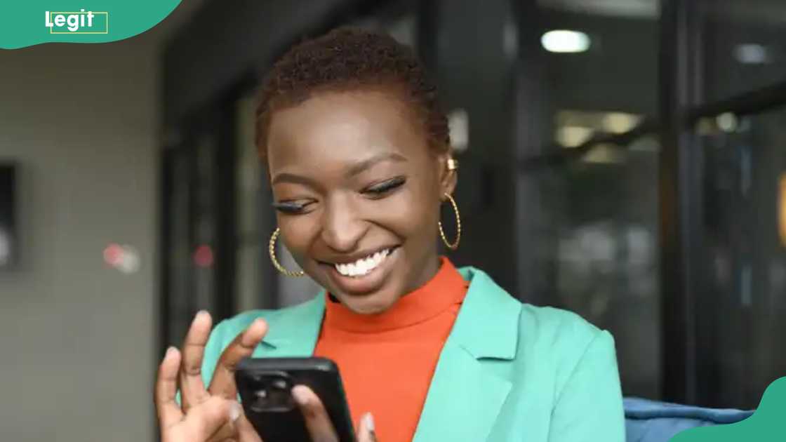 A lady is all smiles as she uses her phone A lady is all smiles as she uses her phone