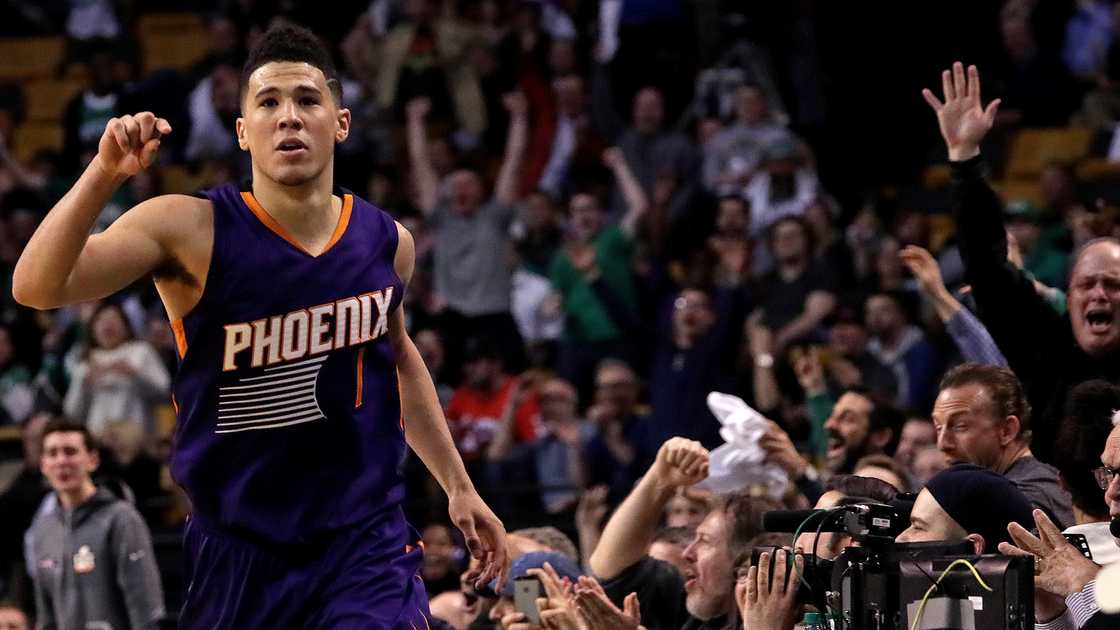Phoenix Suns guard Devin Booker signals as fans cheer on their feet. Phoenix Suns guard Devin Booker signals as fans cheer on their feet.