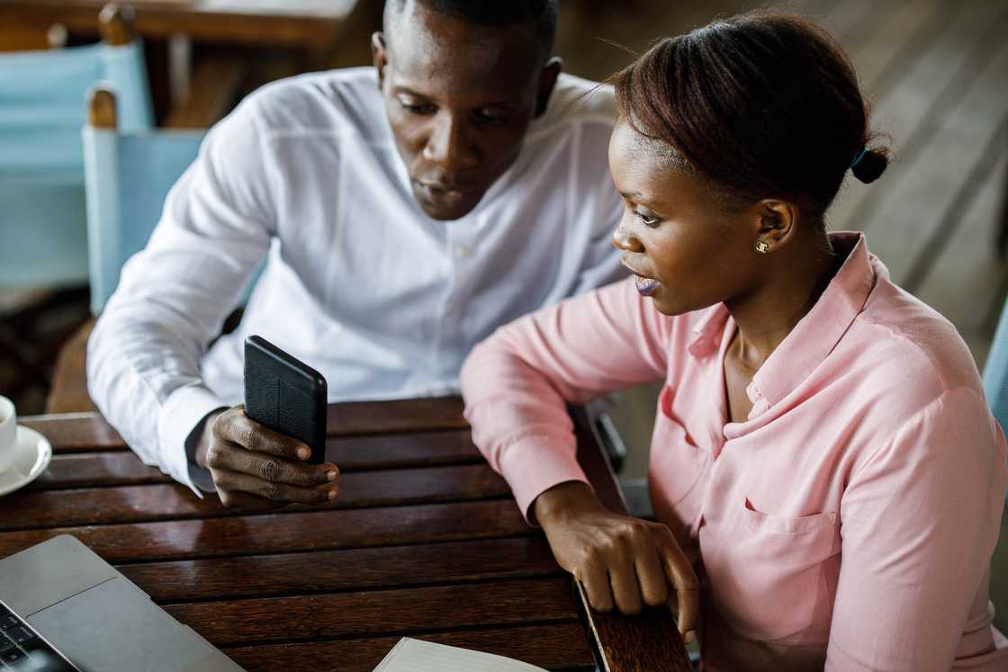 a man showing a woman good news on phone
