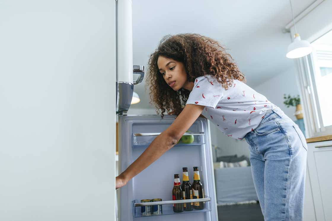 A woman is opening the fridge A woman is opening the fridge