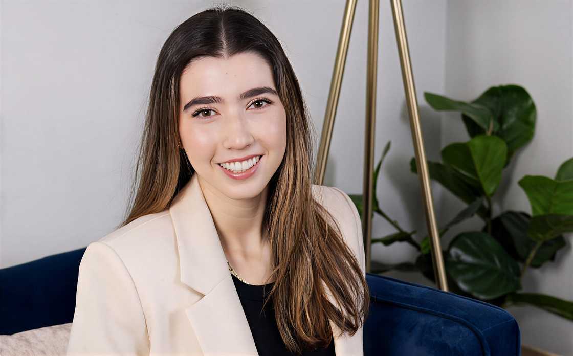 Amy Blagojevich poses sitting on a blue chair in an office setting.