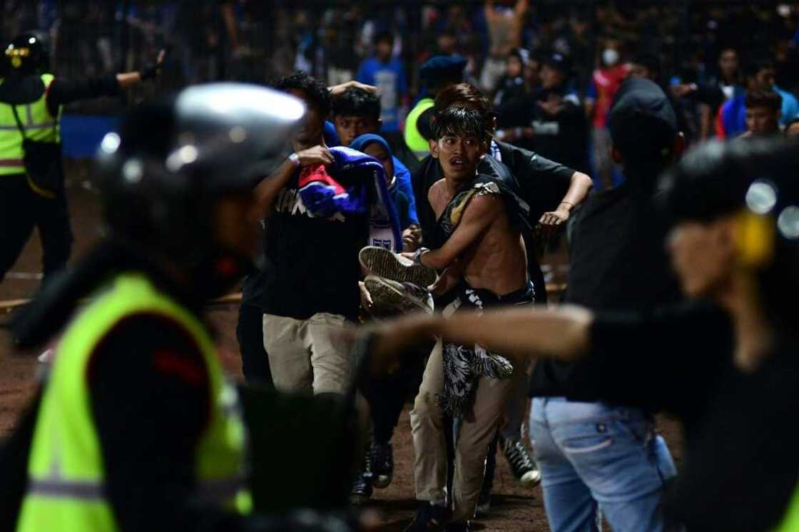 A group of people carry a man off the field at Kanjuruhan stadium on the night of the disaster A group of people carry a man off the field at Kanjuruhan stadium on the night of the disaster