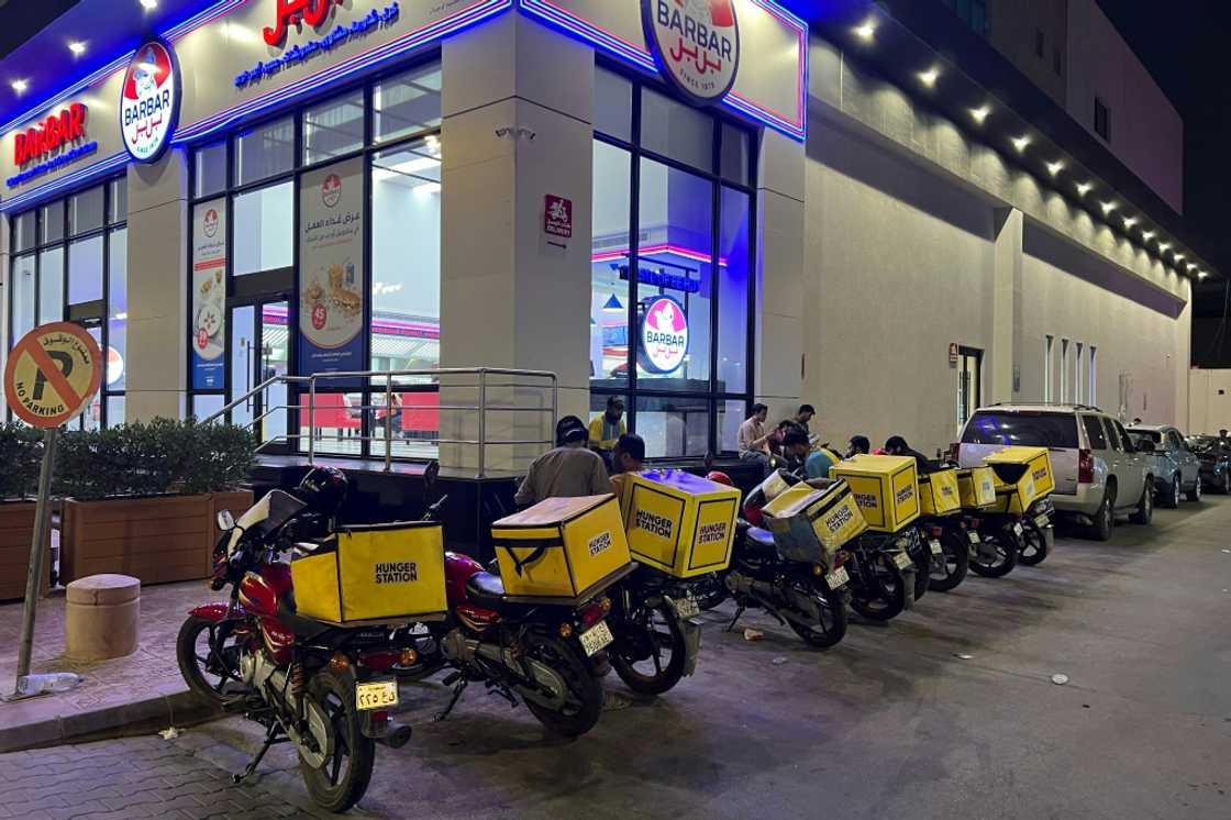 Delivery motorcycles are parked outside an air-conditioned bus station in Riyadh