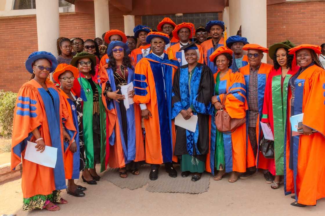 Nnamdi Azikiwe University staff members in orange, blue, and green academic dresses Nnamdi Azikiwe University staff members in orange, blue, and green academic dresses