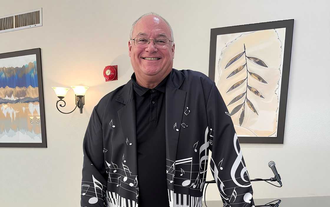 Taylor Bassett poses wearing a black blazer with musical notes and piano key patterns