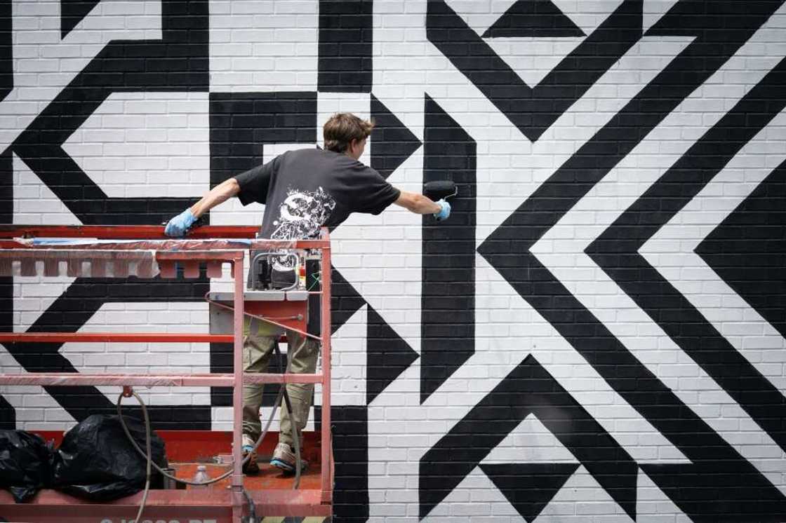 An assistant of mural artist Caroline Monnet paints during the Mural festival in Montreal, Quebec on June 16, 2022 An assistant of mural artist Caroline Monnet paints during the Mural festival in Montreal, Quebec on June 16, 2022