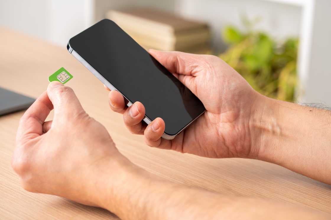 A man putting the sim card on the phone on a table.