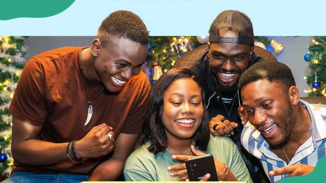 A group of four young people looking at a phone.