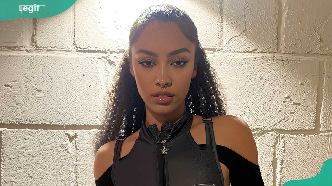 Rubi Rose's younger sister, Coral, in front of a white textured brick wall