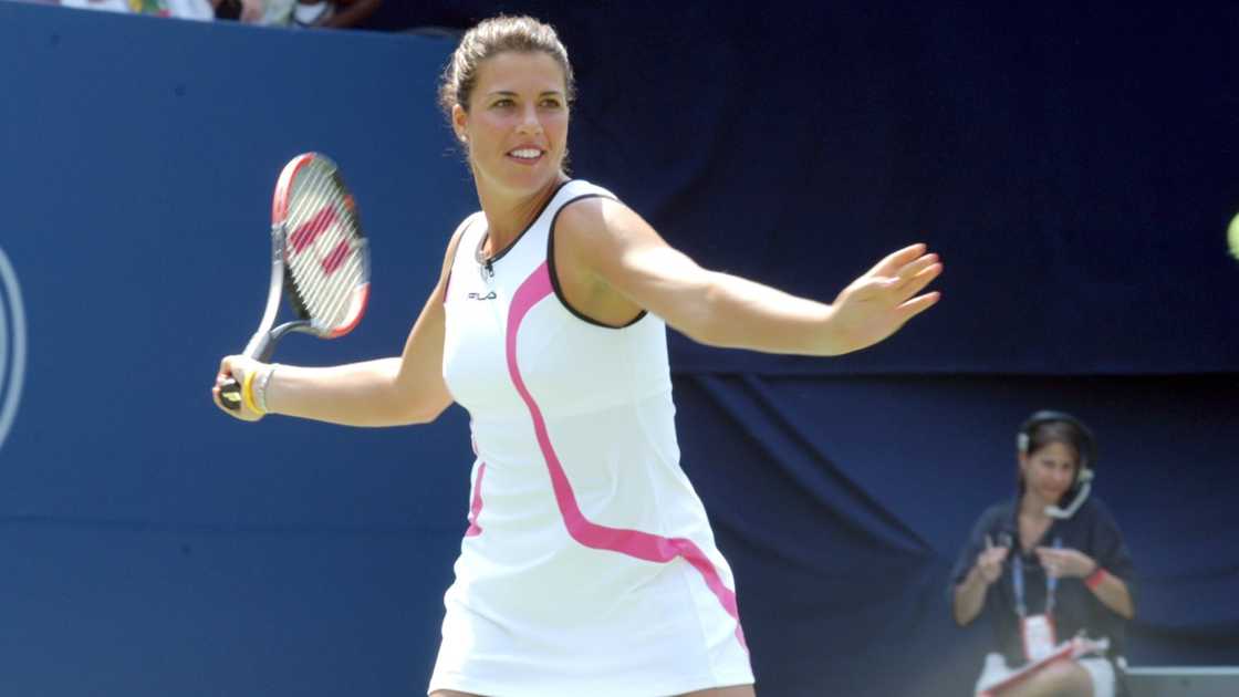 Jennifer Capriati plays tennis in white tennis clothing.