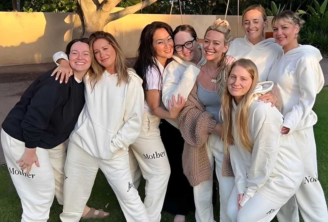 A group of women poses in matching white sweatpants