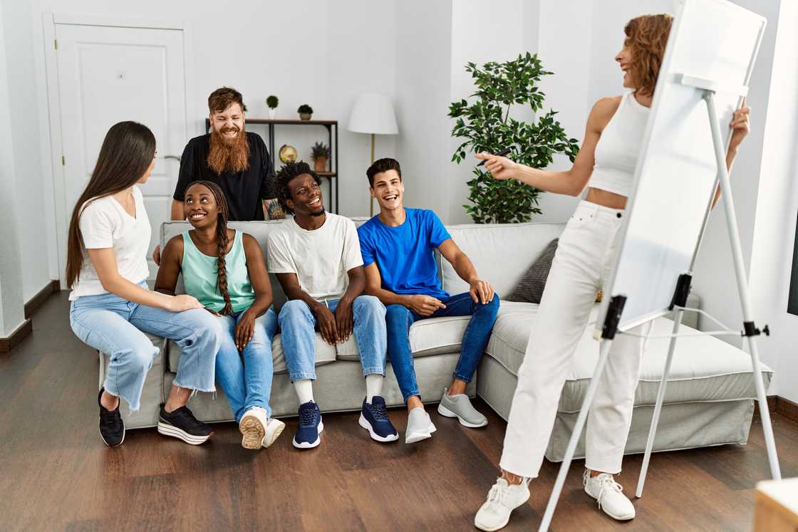 Group of young friends smiling and happy, playing a game at home.