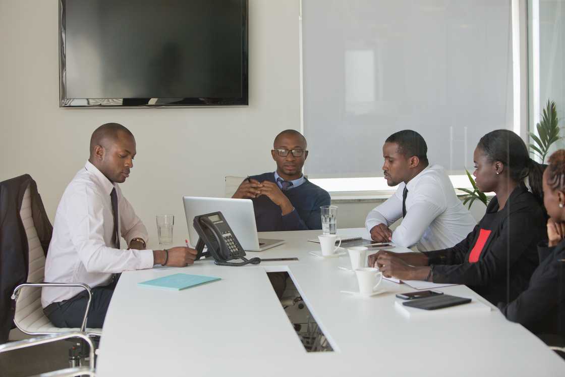 Managers listen to a call playback in an office meeting.