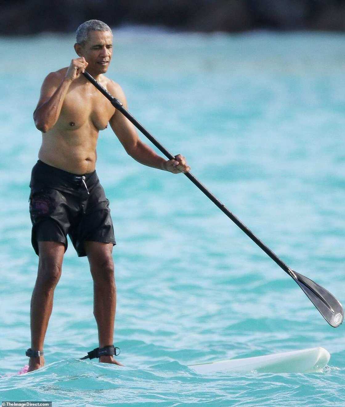 Barack Obama goes paddleboarding shirtless in Hawaii in $84 shark deterrent ankle band