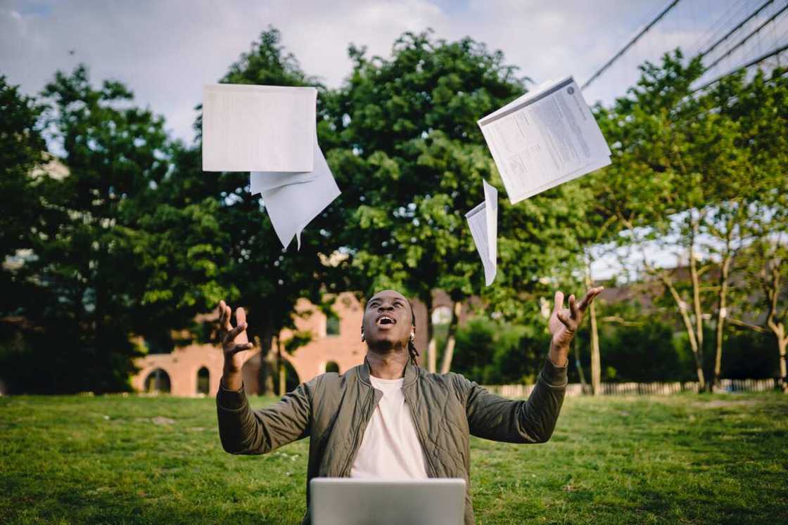 A young man throws papers into the air