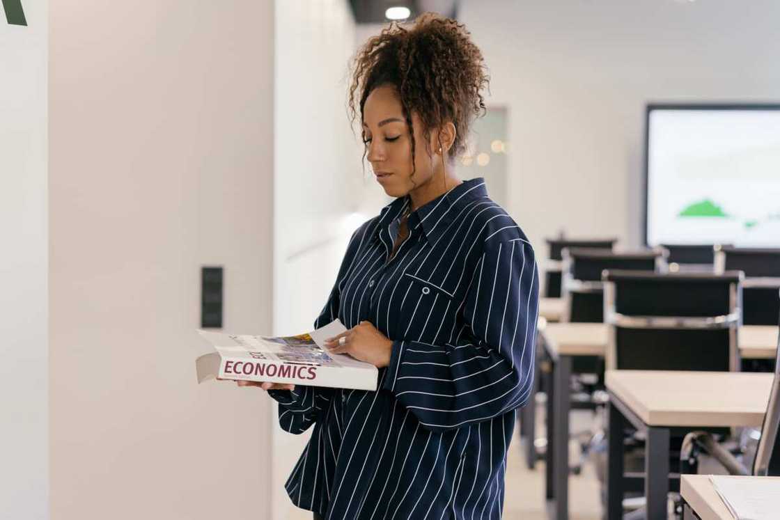 A student holding economics course book A student holding economics course book