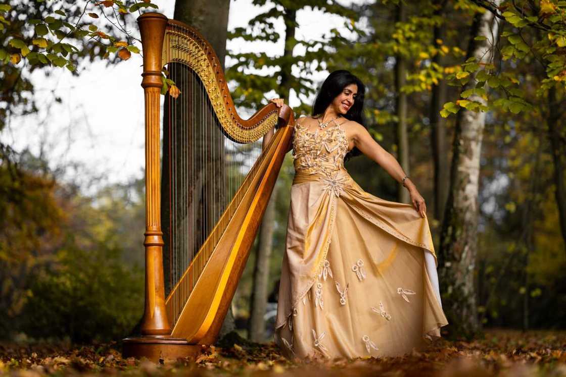 A woman posing with a harp in the forest A woman posing with a harp in the forest