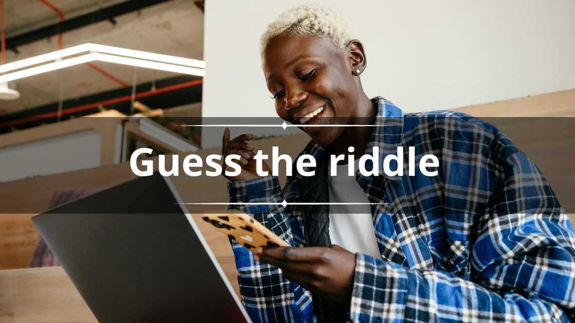 A happy woman in short blonde hair and a blue shirt uses her phone and laptop A happy woman in short blonde hair and a blue shirt uses her phone and laptop