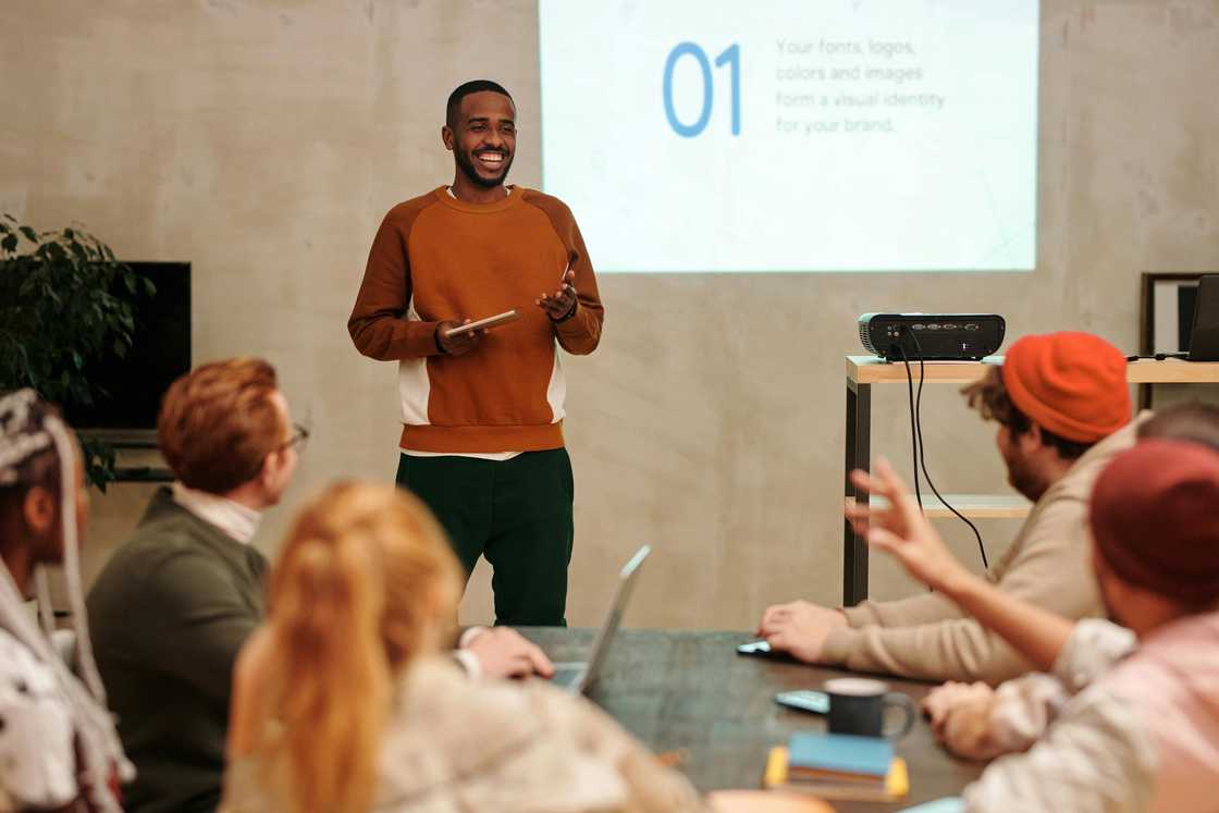 A young man in a sweatshirt is pictured making a presentation using a projector A young man in a sweatshirt is pictured making a presentation using a projector