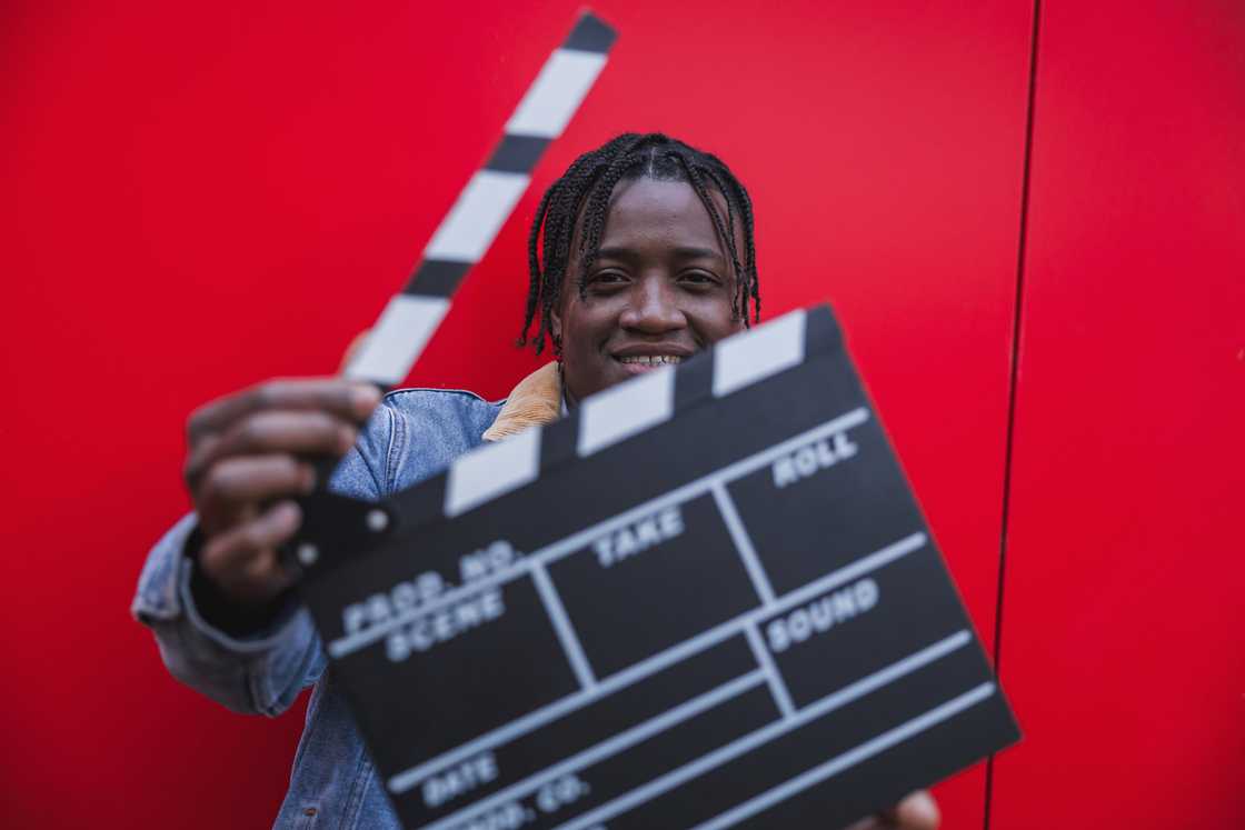A filmmaker's portrait, smiling and holding a clapperboard
