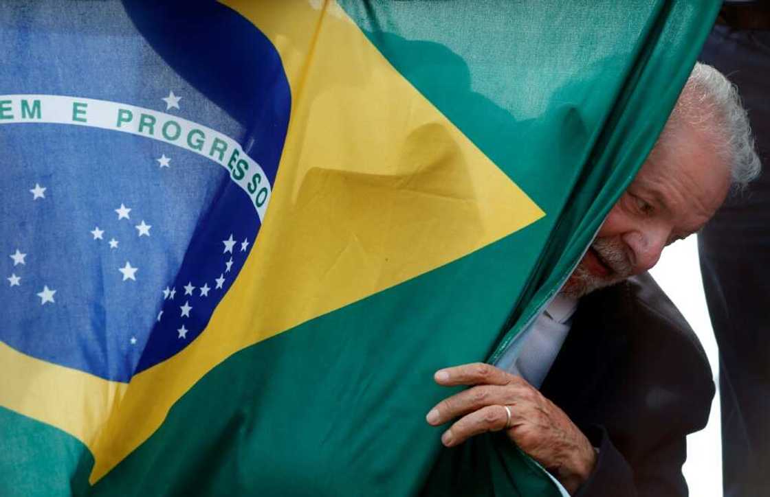 Luiz Inacio Lula da Silva, Brazil's former and newly elected president, appears behind a Brazilian national flag during a campaign rally in Sao Mateus on October 17, 2022