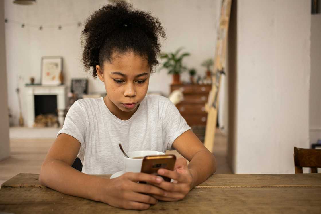 A girl surfing internet on smartphone at table with coffee