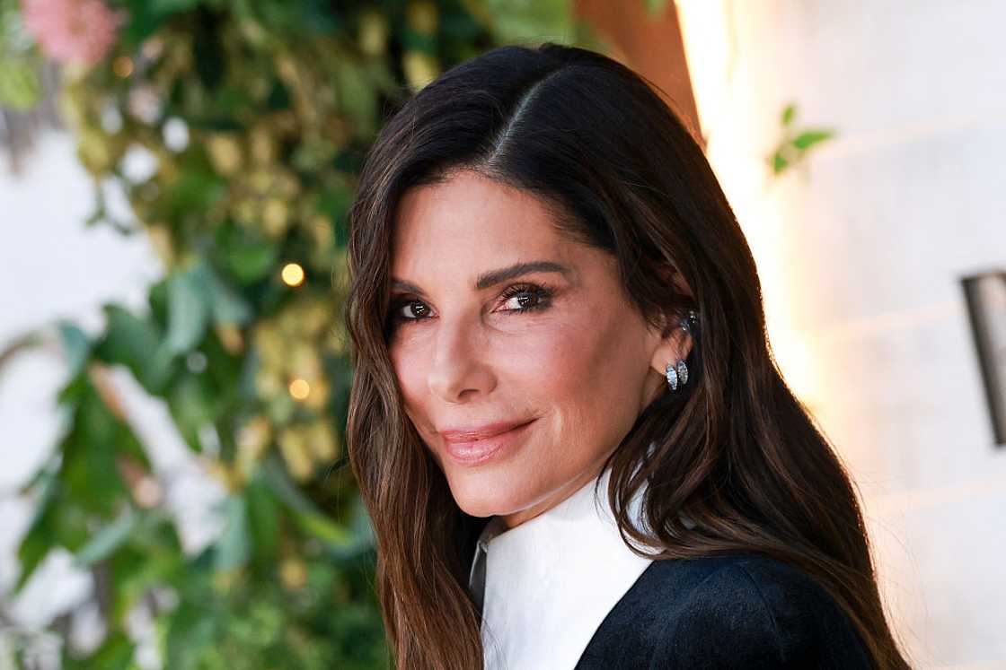 Sandra Bullock smiling at the camera in a black tuxedo-style outfit with a white collar at the US premiere of Practical Magic 2 in Los Angeles, 2026 Sandra Bullock smiling at the camera in a black tuxedo-style outfit with a white collar at the US premiere of Practical Magic 2 in Los Angeles, 2026