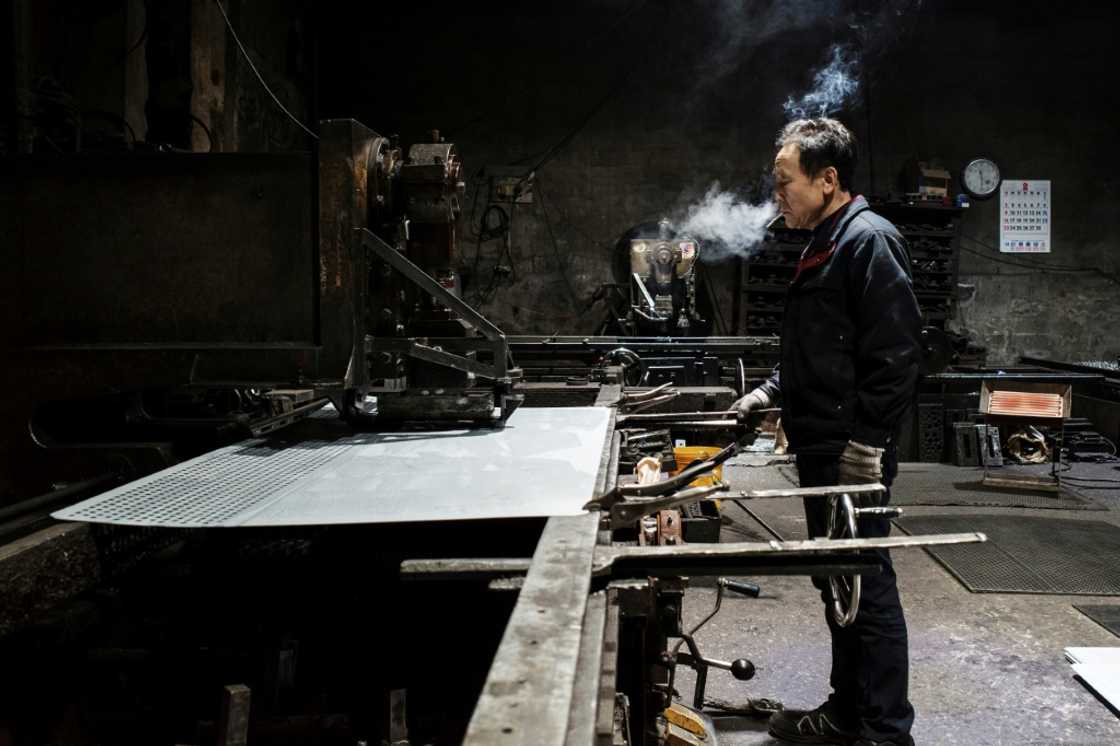 An employee runs a steel sheet through a perforating machine at a metal fabrication plant in Seoul