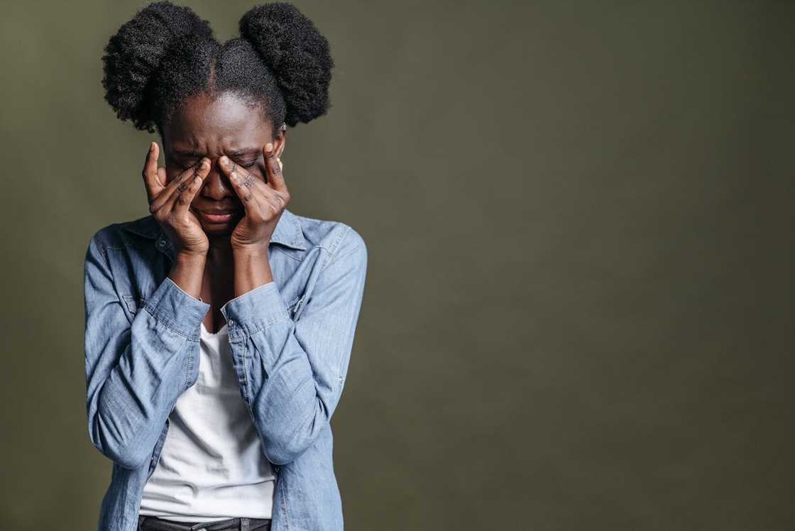 A teenager covers her face with her hands in visible distress.