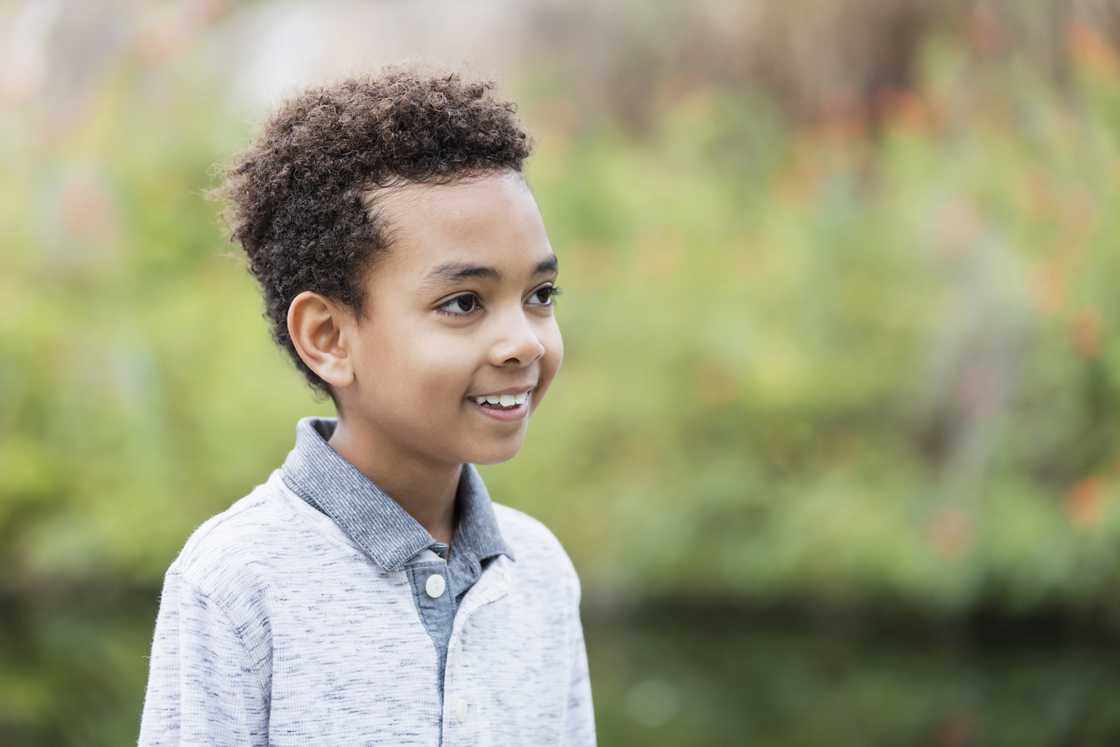 A young boy standing outdoors smiling