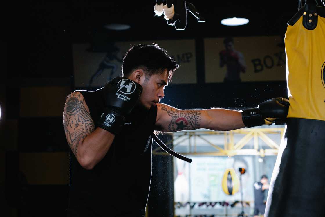A man hitting a heavy bag while practising boxing. A man hitting a heavy bag while practising boxing.