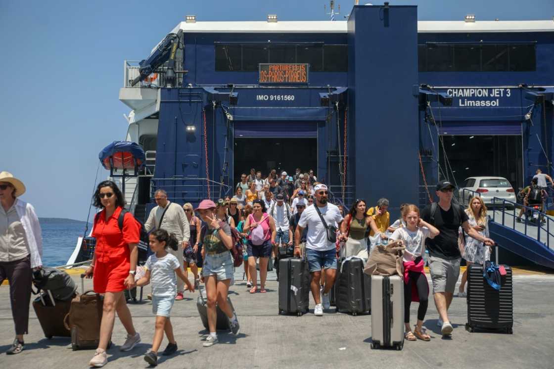 Tourists disembark from a boat at the port