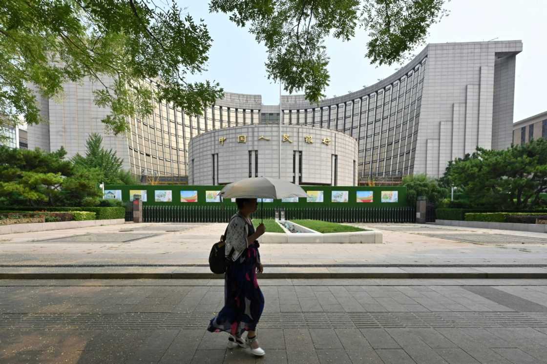 A woman walks past the headquarters of the People’s Bank of China, the country’s central bank, in Beijing on July 9, 2024.