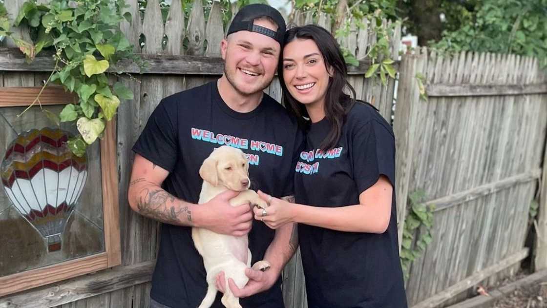 Zach Bryan and Brianna Chickenfry pose standing in identical shirts with their adopted dog, Boston. Zach Bryan and Brianna Chickenfry pose standing in identical shirts with their adopted dog, Boston.